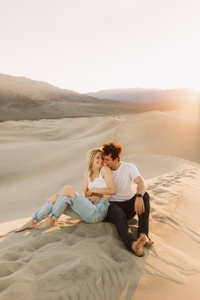 couple snuggling on Mesquite Flats sand dunes at sunset