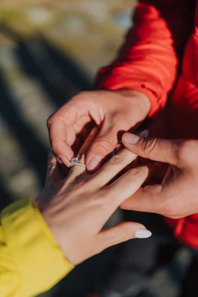 Man slipping engagement ring on finger during a surprise proposal in Switzerland