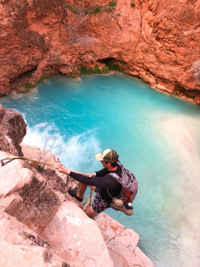 Man using rope to descend down to waterfall 