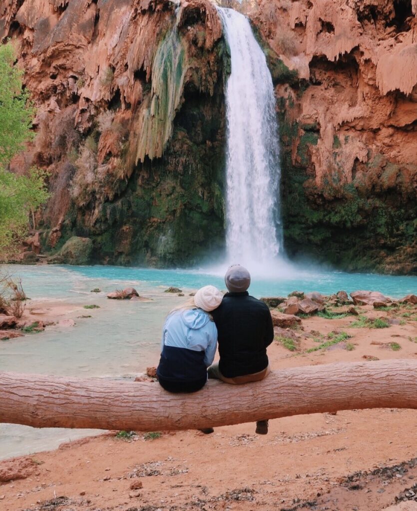 Adventure couple sitting in front of Havasu Falls in Havasupai