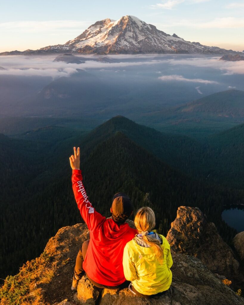 Adventure couple watching the sunset overlooking Mount Rainier from High Rock Lookout