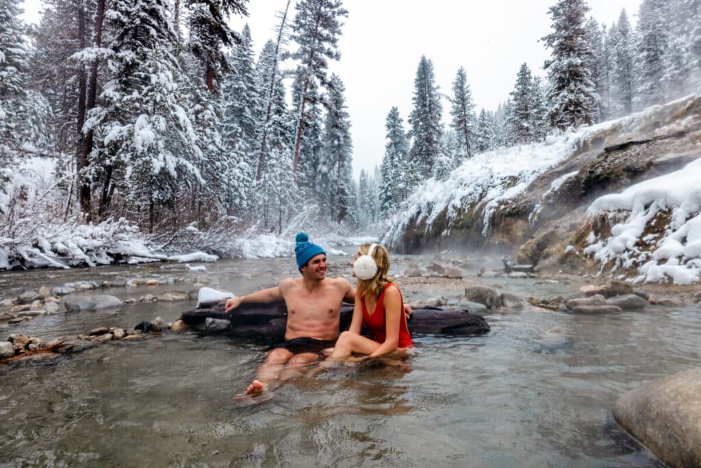 Couple sitting in Bonneville hot springs in Stanley Idaho during winter