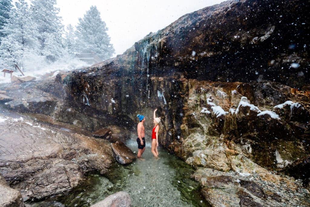 couple standing under Kirkham hot spring waterfall near Stanley Idaho during winter