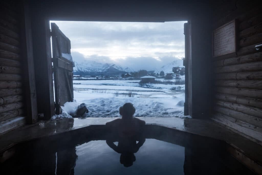 Woman sitting in Mountain Village hot springs in Stanley Idaho during winter