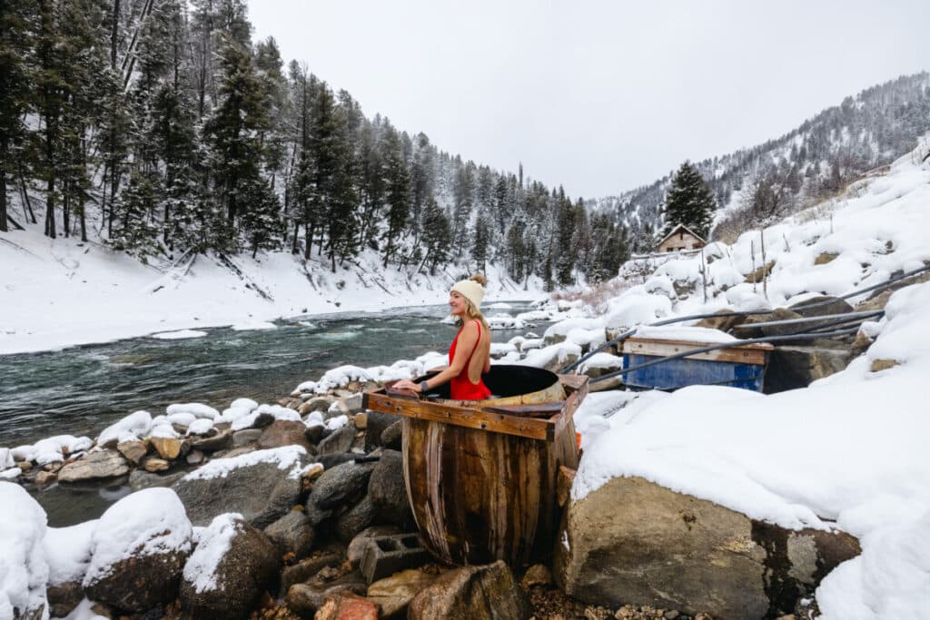Woman sitting in Sunbeam hot springs cauldron tub in Stanley Idaho during winter