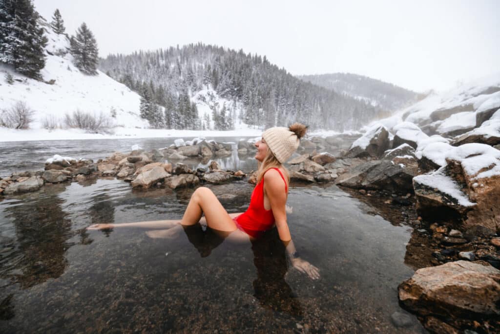 Woman sitting in Boat Box hot springs in Stanley Idaho during winter