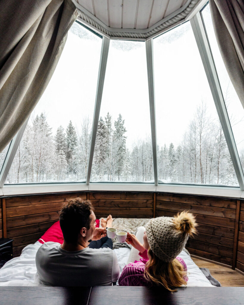 couple toasting inside an aurora glass igloo in Ivalo, Finland