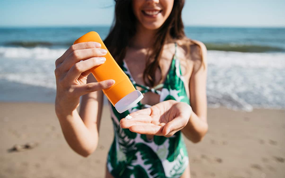 A Woman on a Beach Using Sunscreen