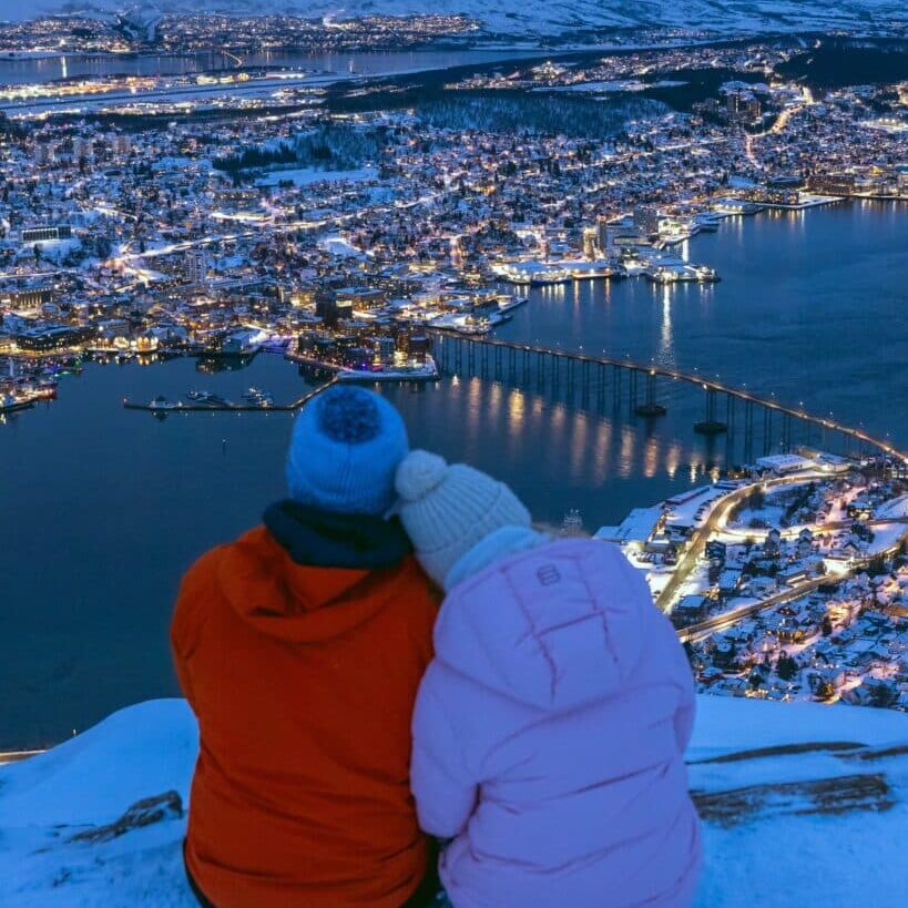 Couple sitting above Tromso, Norway at Cable Car Station